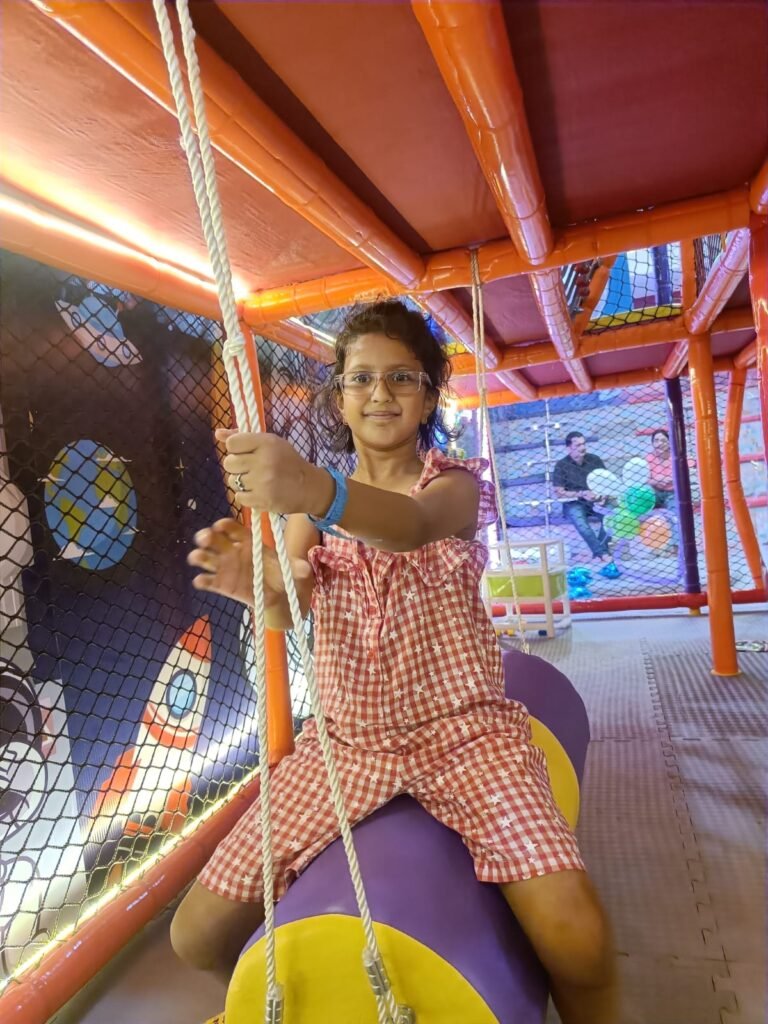 Girl on a swing in the space-themed play structure at Unplug Kids Jind